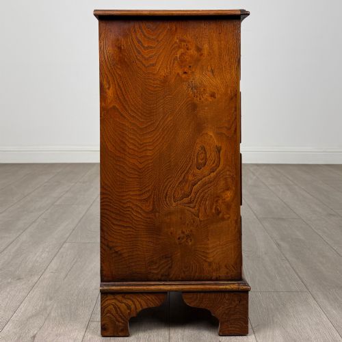 fig 6. A small 20th-century serpentine chest of drawers with four drawers featuring burr walnut veneer, brass drop handles, and bracket feet.