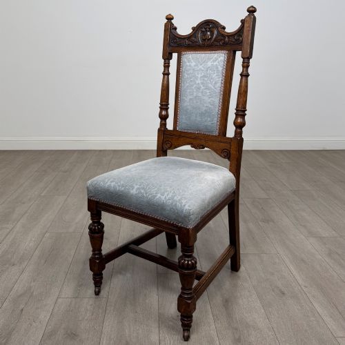fig 1. A set of four 19th-century Victorian dark oak dining chairs featuring carved crest rails, turned legs, and light blue patterned fabric upholstery on the seats and backrests.