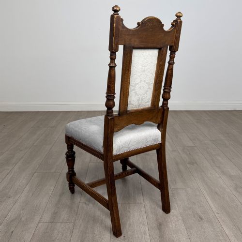 fig 2. A set of four 19th-century Victorian dark oak dining chairs featuring carved crest rails, turned legs, and light blue patterned fabric upholstery on the seats and backrests.