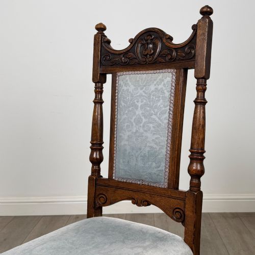 fig 3. A set of four 19th-century Victorian dark oak dining chairs featuring carved crest rails, turned legs, and light blue patterned fabric upholstery on the seats and backrests.