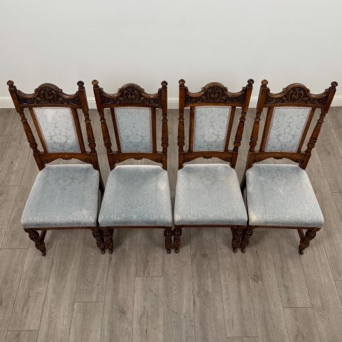 fig 6. A set of four 19th-century Victorian dark oak dining chairs featuring carved crest rails, turned legs, and light blue patterned fabric upholstery on the seats and backrests.
