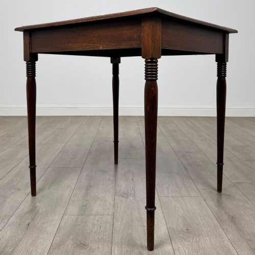 fig 5. An antique Edwardian dark oak side table featuring slender turned legs with ring details and a smooth square top surface.