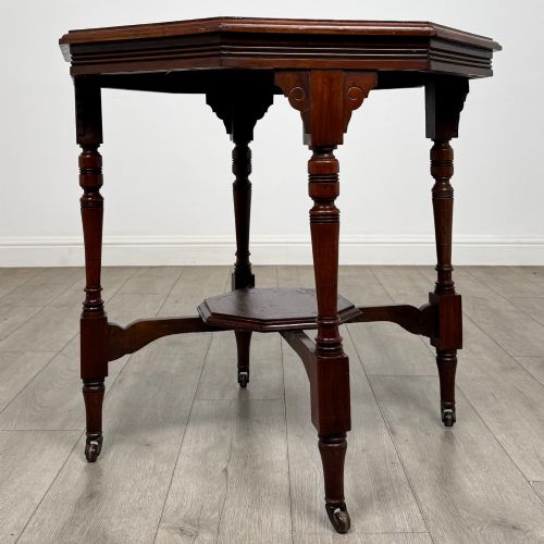 fig 1. An antique mahogany side table featuring an octagonal top, turned legs with castors, and a lower octagonal tier shelf.