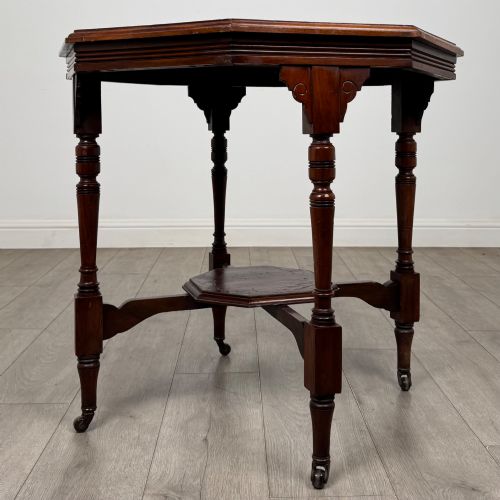 fig 3. An antique mahogany side table featuring an octagonal top, turned legs with castors, and a lower octagonal tier shelf.