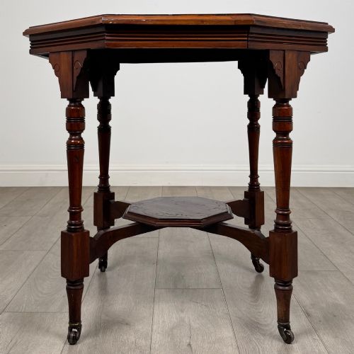 fig 4. An antique mahogany side table featuring an octagonal top, turned legs with castors, and a lower octagonal tier shelf.