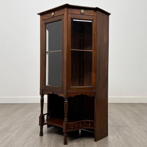 fig 2. An antique walnut display cabinet featuring glazed door and side panels, decorative inlay along the frieze, and an open lower shelf resting on turned front legs.
