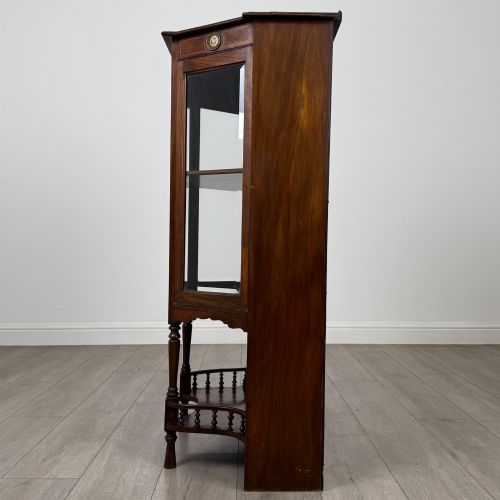 fig 3. An antique walnut display cabinet featuring glazed door and side panels, decorative inlay along the frieze, and an open lower shelf resting on turned front legs.