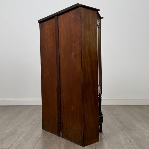 fig 6. An antique walnut display cabinet featuring glazed door and side panels, decorative inlay along the frieze, and an open lower shelf resting on turned front legs.