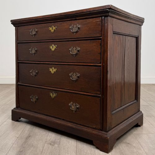 fig 1. An 18th-century dark oak Georgian chest of drawers featuring four graduated drawers with brass handles and keyhole escutcheons.