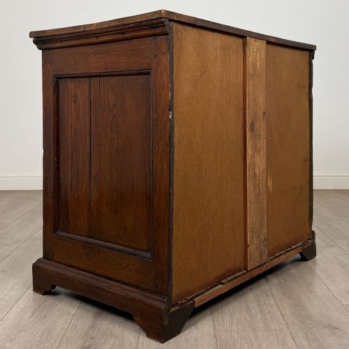 fig 3. An 18th-century dark oak Georgian chest of drawers featuring four graduated drawers with brass handles and keyhole escutcheons.