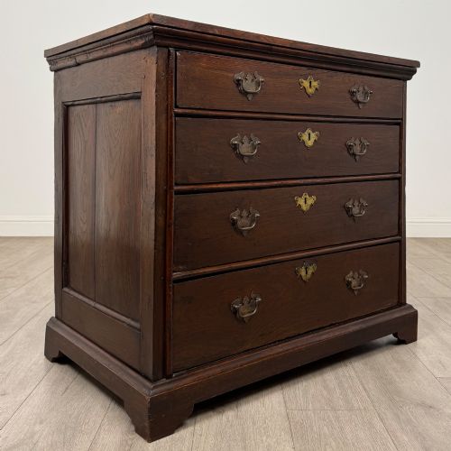 fig 7. An 18th-century dark oak Georgian chest of drawers featuring four graduated drawers with brass handles and keyhole escutcheons.