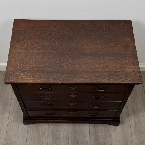 fig 8. An 18th-century dark oak Georgian chest of drawers featuring four graduated drawers with brass handles and keyhole escutcheons.