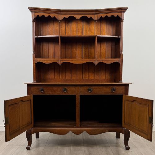 fig 1. A 20th-century golden oak Welsh dresser featuring a three-tiered open shelf top section over a two-door, two-drawer base with cabriole legs.