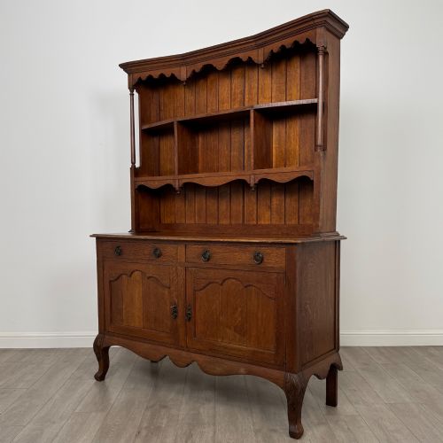 fig 2. A 20th-century golden oak Welsh dresser featuring a three-tiered open shelf top section over a two-door, two-drawer base with cabriole legs.