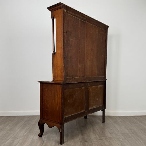 fig 4. A 20th-century golden oak Welsh dresser featuring a three-tiered open shelf top section over a two-door, two-drawer base with cabriole legs.