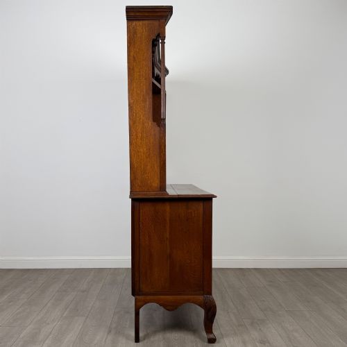 fig 7. A 20th-century golden oak Welsh dresser featuring a three-tiered open shelf top section over a two-door, two-drawer base with cabriole legs.