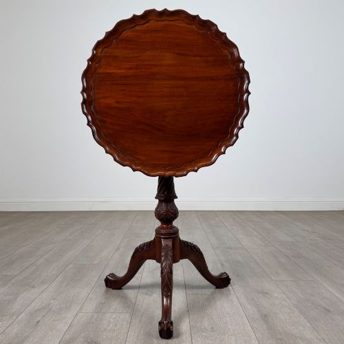 fig 1. A dark mahogany tripod occasional table featuring a piecrust scalloped top, a birdcage mechanism, a spiral turned column, and leaf-carved legs.