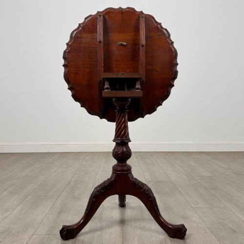 fig 2. A dark mahogany tripod occasional table featuring a piecrust scalloped top, a birdcage mechanism, a spiral turned column, and leaf-carved legs.