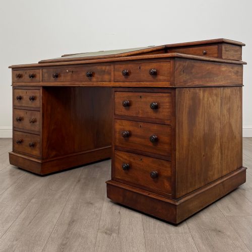 fig 1. A 19th-century Victorian mahogany Dickens desk featuring a sloped green leather writing top, a raised rear superstructure, and twin pedestals fitted with turned knobs.