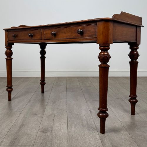 fig 1. A 19th-century mahogany writing table featuring two frieze drawers with wooden turned handles, standing on four turned legs.