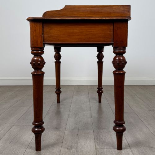 fig 2. A 19th-century mahogany writing table featuring two frieze drawers with wooden turned handles, standing on four turned legs.