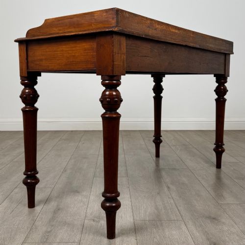 fig 3. A 19th-century mahogany writing table featuring two frieze drawers with wooden turned handles, standing on four turned legs.