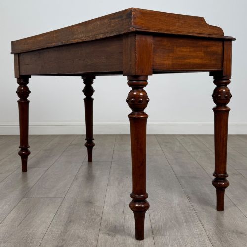 fig 5. A 19th-century mahogany writing table featuring two frieze drawers with wooden turned handles, standing on four turned legs.