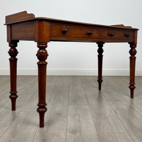 fig 7. A 19th-century mahogany writing table featuring two frieze drawers with wooden turned handles, standing on four turned legs.