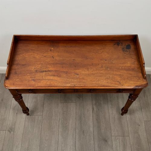 fig 8. A 19th-century mahogany writing table featuring two frieze drawers with wooden turned handles, standing on four turned legs.