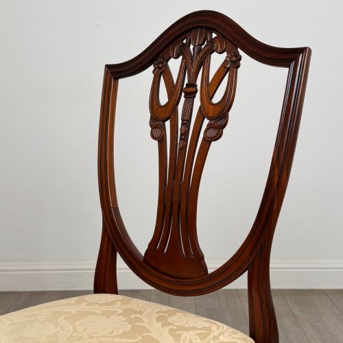 fig 3. A set of eight mahogany shield back dining chairs featuring intricate pierced back splats and light cream upholstered seats.