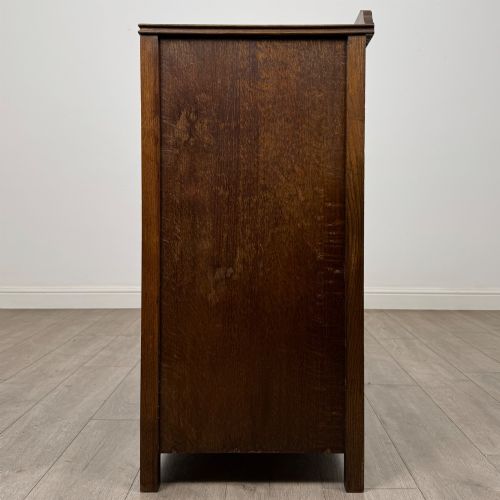 fig 2. Front view of an early 20th-century warm brown oak chest featuring four wide drawers with ornamental brass drop handles.