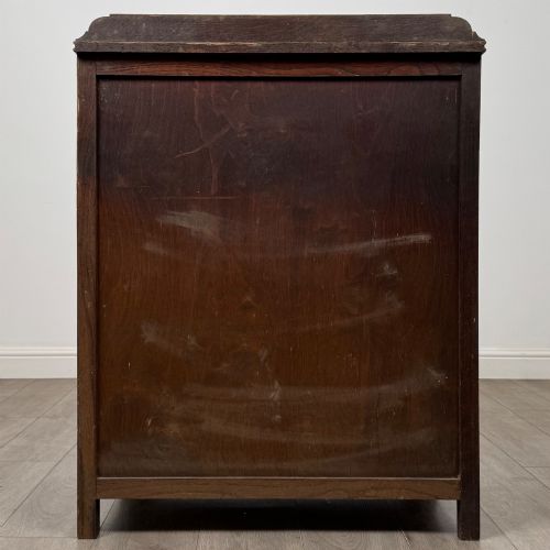 fig 4. Front view of an early 20th-century warm brown oak chest featuring four wide drawers with ornamental brass drop handles.