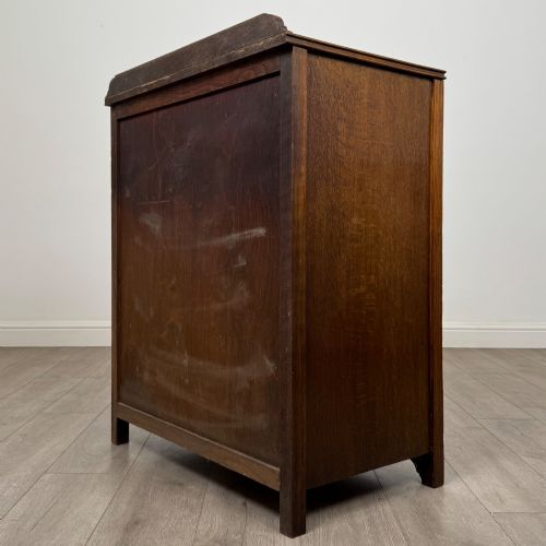 fig 5. Front view of an early 20th-century warm brown oak chest featuring four wide drawers with ornamental brass drop handles.