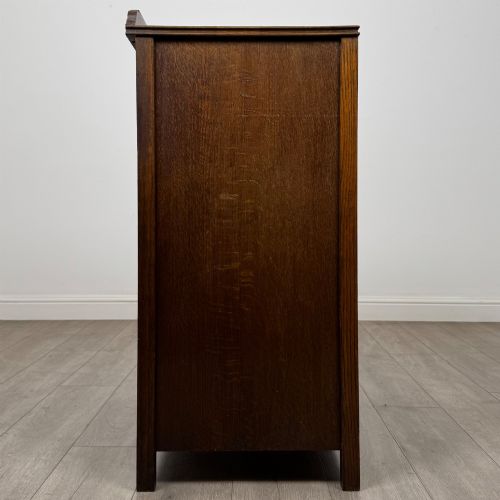 fig 6. Front view of an early 20th-century warm brown oak chest featuring four wide drawers with ornamental brass drop handles.