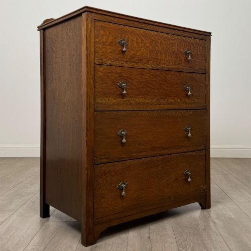 fig 7. Front view of an early 20th-century warm brown oak chest featuring four wide drawers with ornamental brass drop handles.