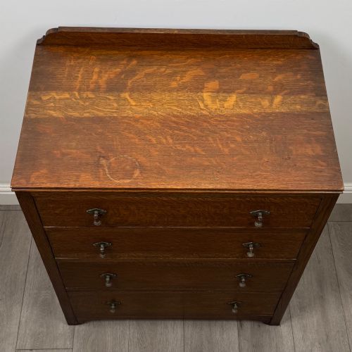 fig 8. Front view of an early 20th-century warm brown oak chest featuring four wide drawers with ornamental brass drop handles.