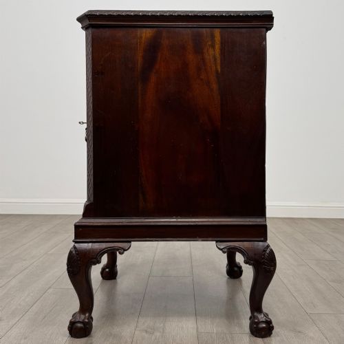 fig 3. A dark mahogany Chippendale style cupboard featuring a single door with an oval flame mahogany panel, carved borders, and cabriole legs with ball-and-claw feet.