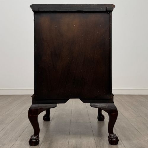 fig 5. A dark mahogany Chippendale style cupboard featuring a single door with an oval flame mahogany panel, carved borders, and cabriole legs with ball-and-claw feet.