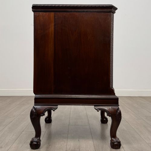 fig 7. A dark mahogany Chippendale style cupboard featuring a single door with an oval flame mahogany panel, carved borders, and cabriole legs with ball-and-claw feet.
