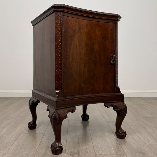 fig 8. A dark mahogany Chippendale style cupboard featuring a single door with an oval flame mahogany panel, carved borders, and cabriole legs with ball-and-claw feet.