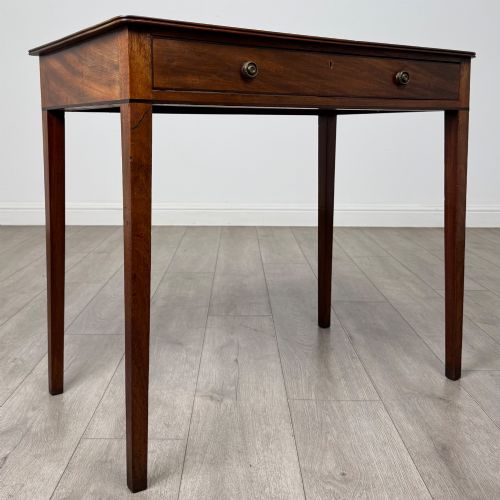 fig 7. An 18th-century Georgian mahogany writing table featuring a single drawer with brass handles and four square tapered legs.