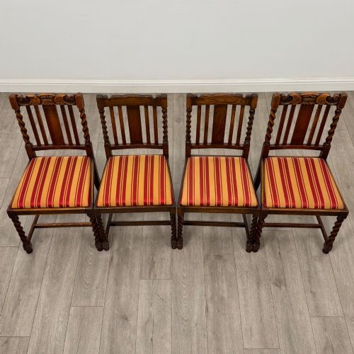 fig 7. A set of ten early twentieth-century oak dining chairs featuring barley twist turned legs and supports with red and yellow striped upholstered seats.