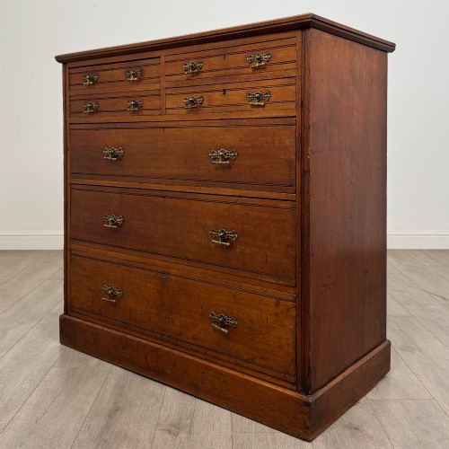 fig 1. An antique walnut chest of drawers featuring decorative brass handles, reeded top drawer fronts, and a solid plinth base.
