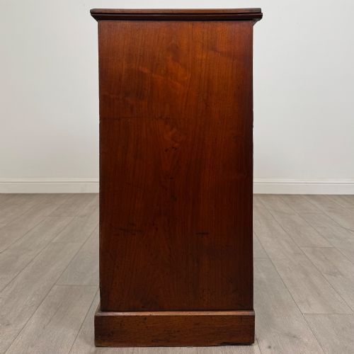 fig 2. An antique walnut chest of drawers featuring decorative brass handles, reeded top drawer fronts, and a solid plinth base.