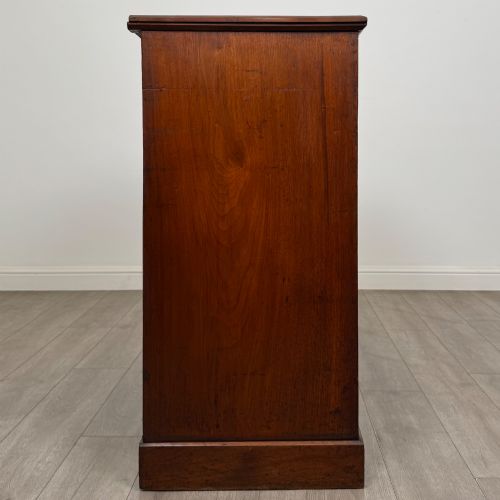 fig 6. An antique walnut chest of drawers featuring decorative brass handles, reeded top drawer fronts, and a solid plinth base.