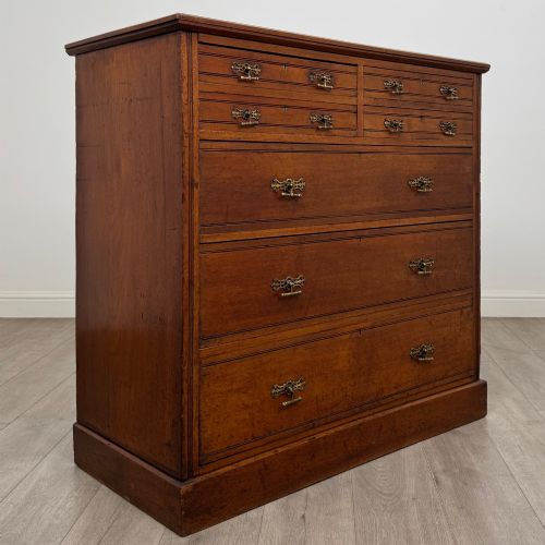 fig 7. An antique walnut chest of drawers featuring decorative brass handles, reeded top drawer fronts, and a solid plinth base.