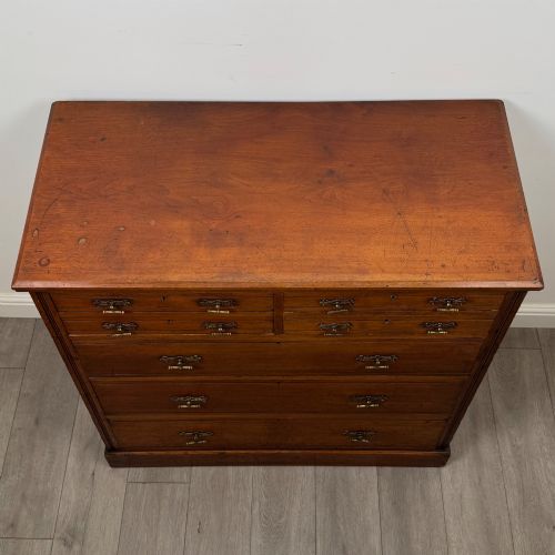 fig 8. An antique walnut chest of drawers featuring decorative brass handles, reeded top drawer fronts, and a solid plinth base.