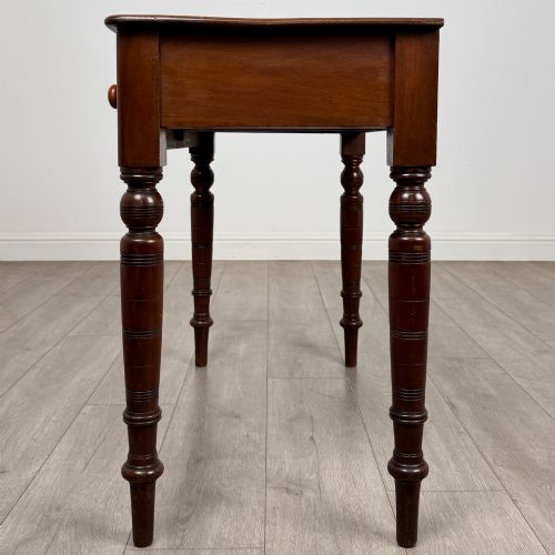 fig 2. A Victorian mahogany writing table featuring two frieze drawers with wooden knobs and turned reeded legs.