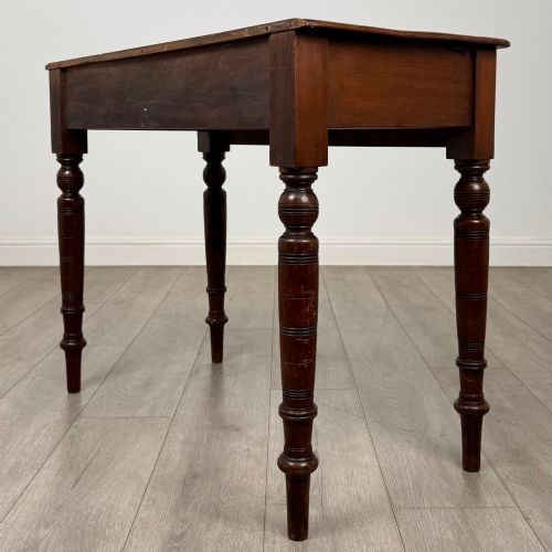 fig 5. A Victorian mahogany writing table featuring two frieze drawers with wooden knobs and turned reeded legs.