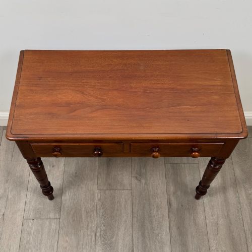 fig 8. A Victorian mahogany writing table featuring two frieze drawers with wooden knobs and turned reeded legs.